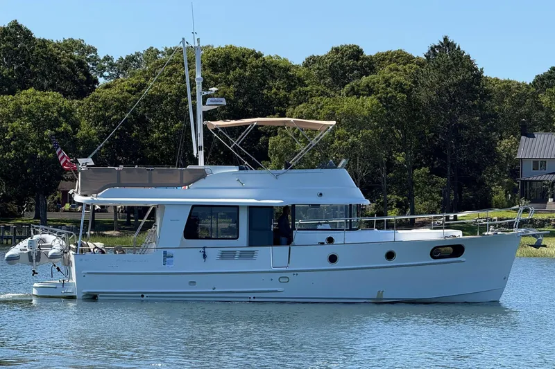 Slide: The Image of 2018 Beneteau Swift Trawler 44 on calm water, surrounded by lush greenery. - 3