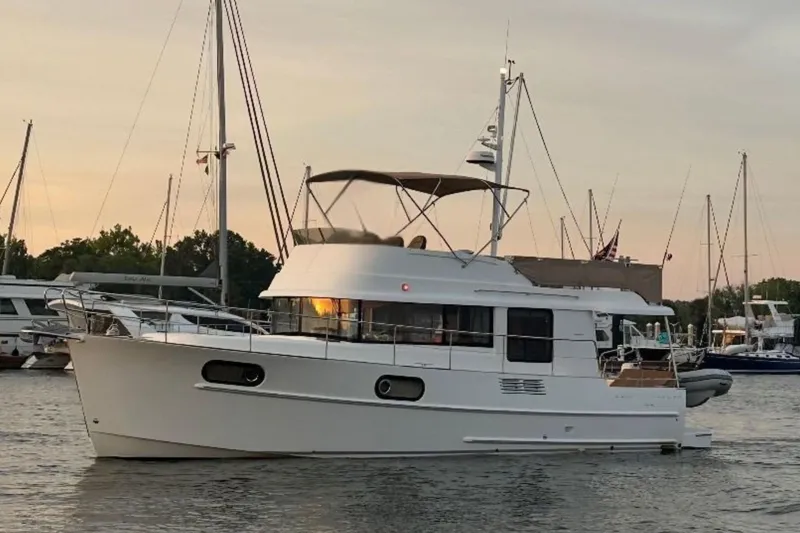 Slide: The Image of 2018 Beneteau Swift Trawler 44 yacht docked at sunset, surrounded by sailboats. - 5