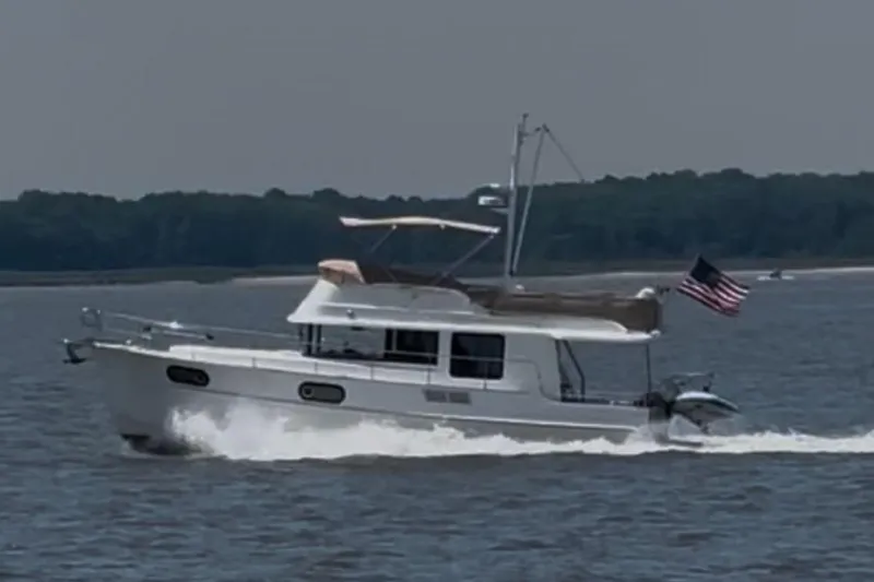 Slide: The Image of 2018 Beneteau Swift Trawler 44 cruising on a calm lake with an American flag. - 6