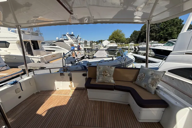 Slide: The Image of 2018 Beneteau Swift Trawler 44, elegant deck with cushioned seating, docked at marina. - 9