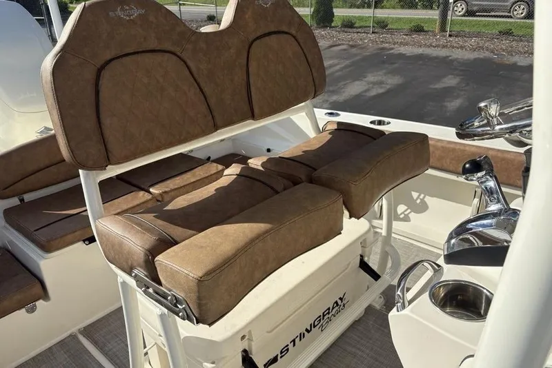 Slide: The Image of 2021 Stingray 236CC boat interior with brown cushioned seating and steering controls. - 26