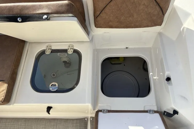 Slide: The Image of 2021 Stingray 236CC boat storage compartments with open hatches, featuring brown cushioned seating. - 33