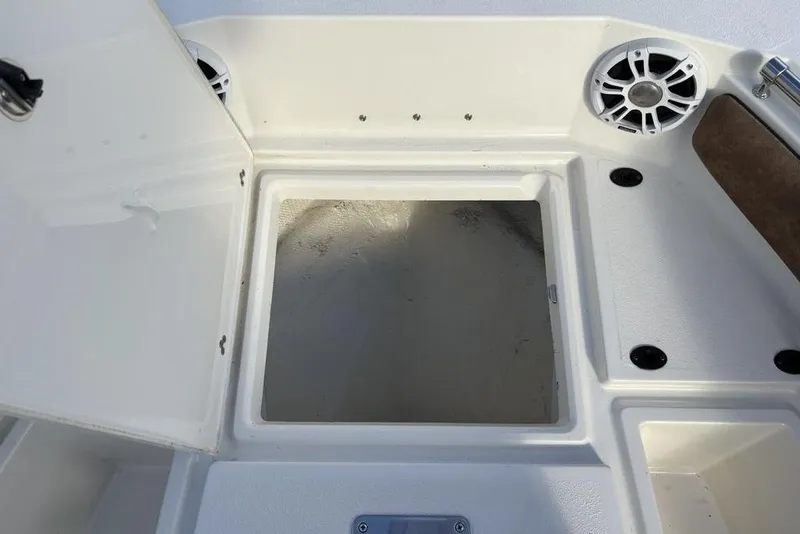 Slide: The Image of Open storage compartment on a 2021 Stingray 236CC boat deck, featuring speakers and seating. - 8