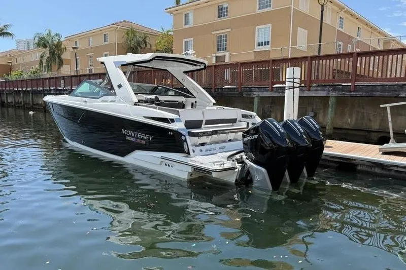 Slide: The Image of 2023 Monterey 385 Super Sport boat docked in a marina, featuring triple Mercury engines. - 11