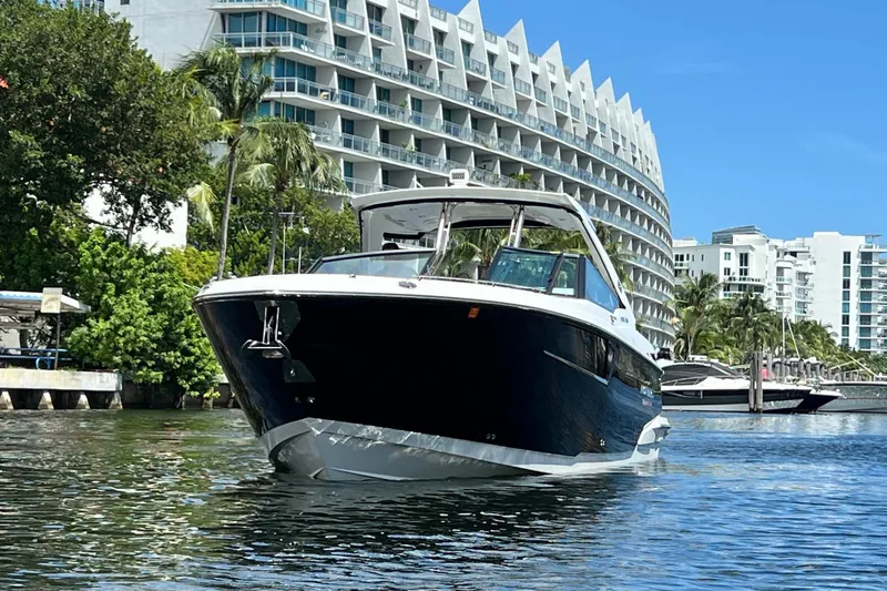 Slide: The Image of 2023 Monterey 385 Super Sport boat on water near modern buildings and palm trees. - 2