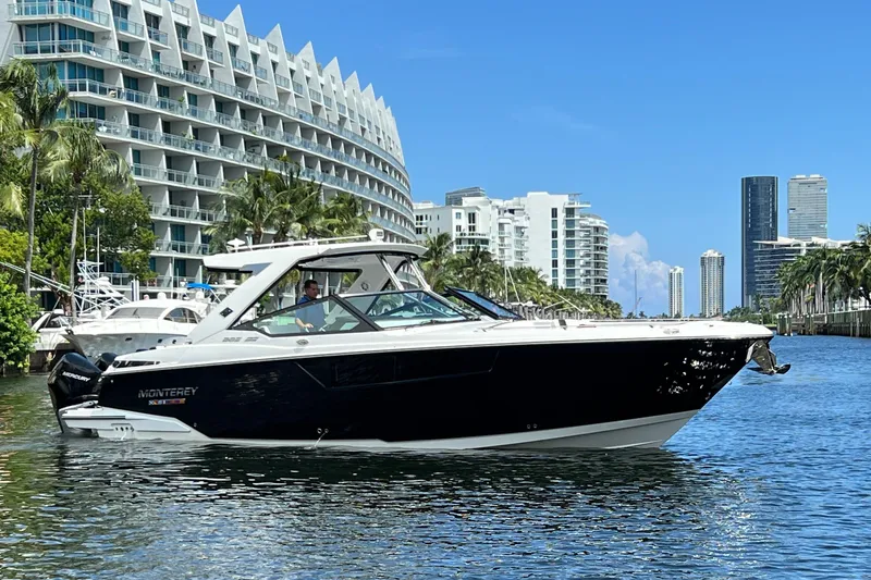 Slide: The Image of 2023 Monterey 385 Super Sport boat cruising near modern waterfront buildings. - 56