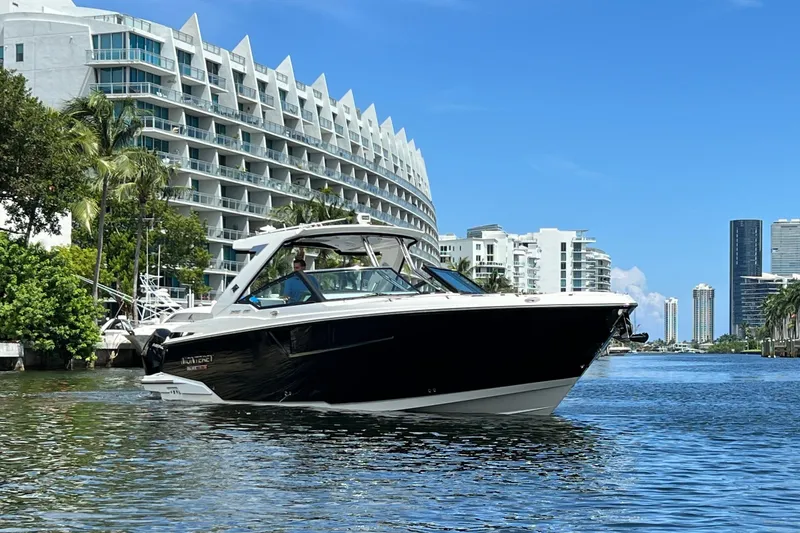 Slide: The Image of 2023 Monterey 385 Super Sport boat cruising near modern waterfront buildings. - 57