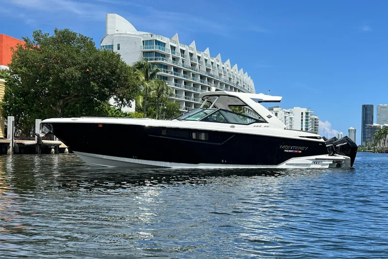 Slide: The Image of 2023 Monterey 385 Super Sport boat cruising on a sunny waterfront with modern buildings. - 61