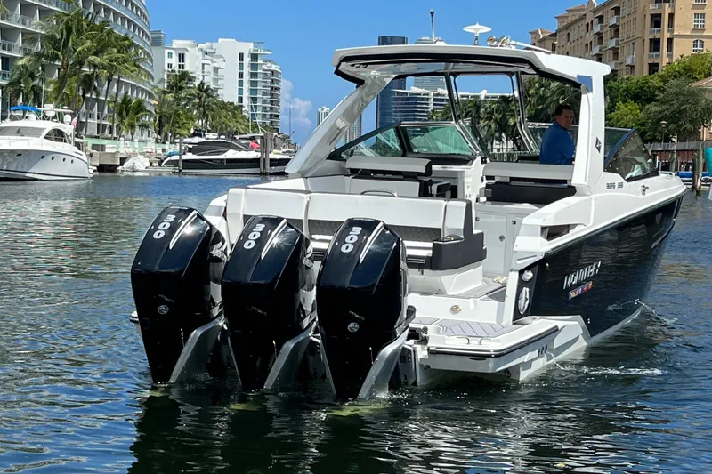 Slide: The Image of 2023 Monterey 385 Super Sport boat with triple outboard engines in a marina setting. - 8