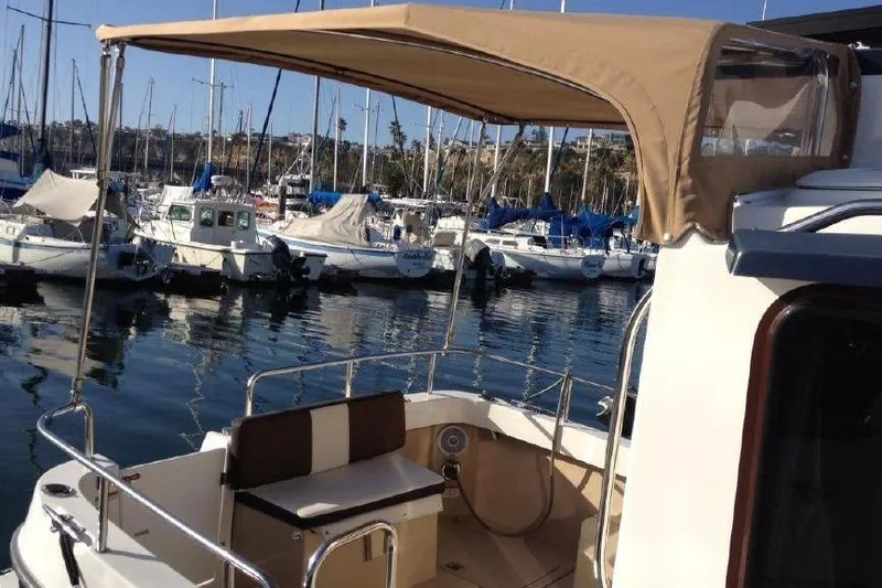 Slide: The Image of 2016 Ranger Tugs R25 SC boat docked in marina, featuring a shaded seating area. - 5