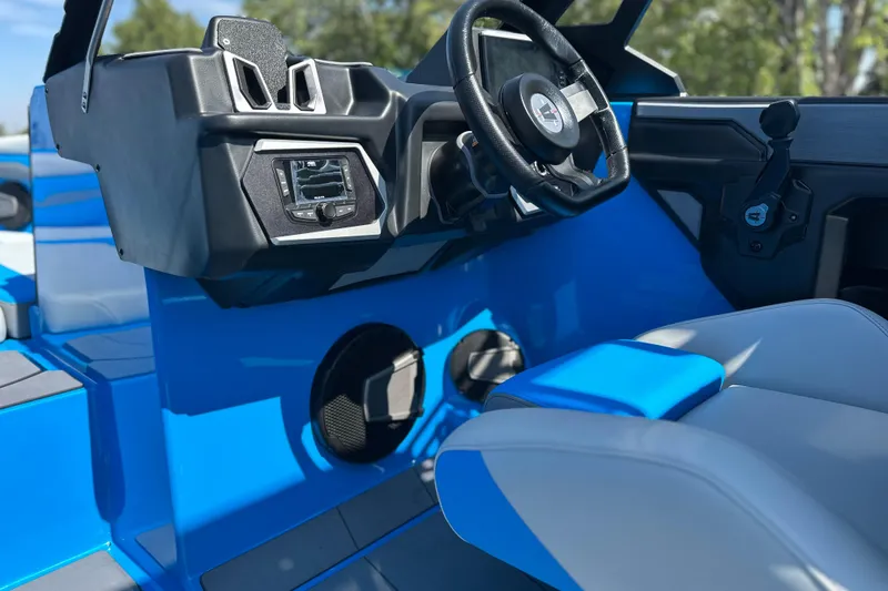Slide: The Image of 2026 Axis T235 boat interior with steering wheel and control panel, featuring blue and gray seating. - 13