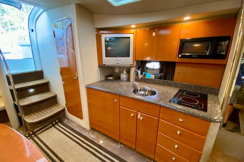 Slide: The Image of 2004 Formula 37 PC yacht interior with kitchenette, featuring wood cabinets, sink, and appliances. - 23