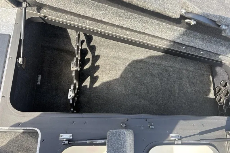 Slide: The Image of Open storage compartment in 2008 Skeeter ZX190 boat, featuring rod holders and carpeted interior. - 9