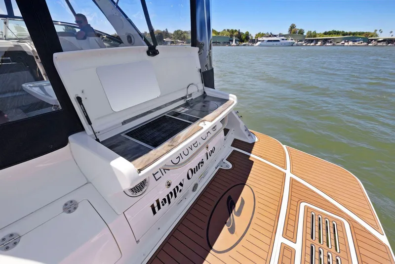 Slide: The Image of 2014 Sea Ray 350 Sundancer boat with outdoor grill on deck, docked by the water. - 11