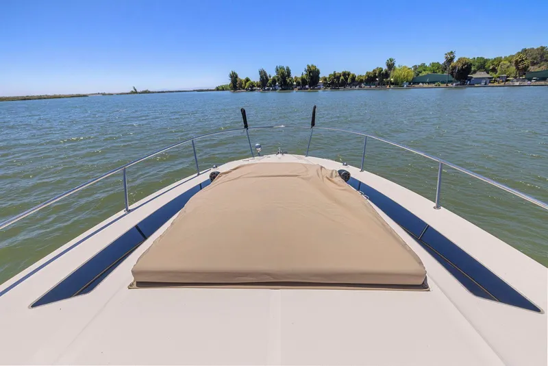 Slide: The Image of 2014 Sea Ray 350 Sundancer boat deck with sunpad, overlooking calm waters and distant shoreline. - 7