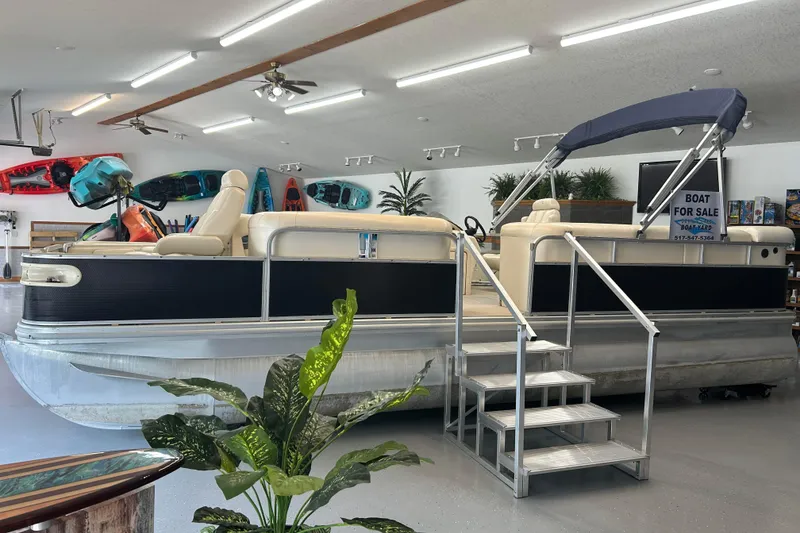 Slide: The Image of 2005 Bennington 2250RFS pontoon boat for sale in showroom with kayaks displayed. - 0