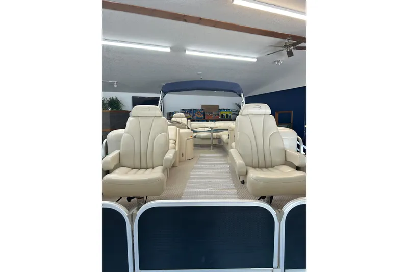 Slide: The Image of 2005 Bennington 2250RFS pontoon boat with beige seating and blue canopy in showroom. - 2