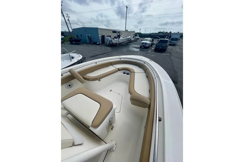 Slide: The Image of 2021 Pioneer 222 Islander boat with tan seating, parked in a lot with vehicles. - 5