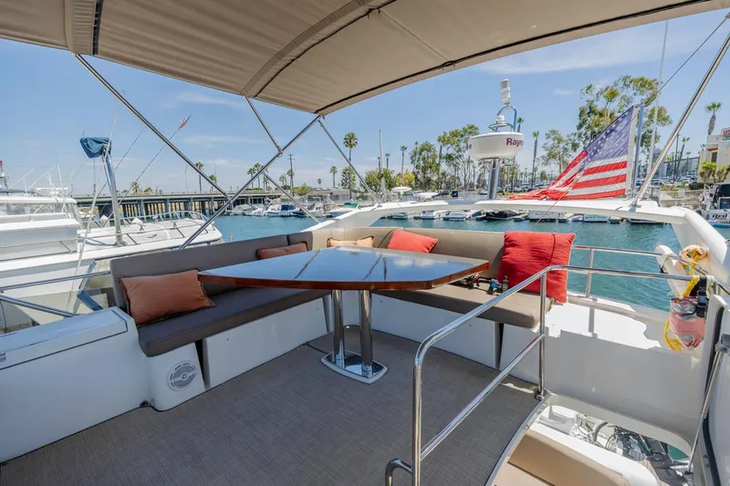 Slide: The Image of Flybridge of 2015 Prestige 500FB yacht with seating, table, and American flag in marina. - 27