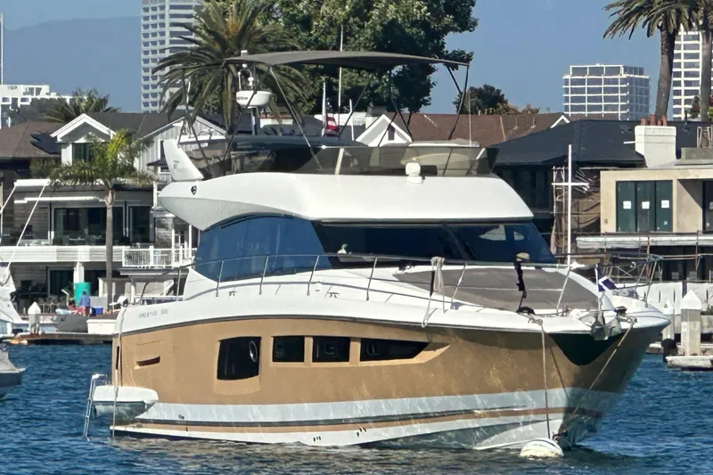 Slide: The Image of 2015 Prestige 500FB yacht docked in a marina, surrounded by modern buildings and palm trees. - 59