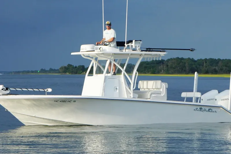 Slide: The Image of 2022 SeaHunter 28 Floridian boat on calm water with a person at the helm. - 11
