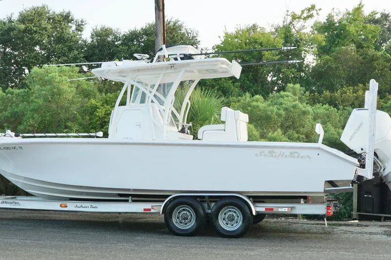 Slide: The Image of 2022 SeaHunter 28 Floridian boat on trailer, surrounded by lush greenery. - 13