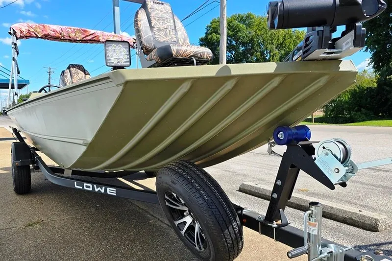 Slide: The Image of 2022 Lowe Roughneck RX1860 Rambler boat on trailer, featuring camouflage seats and mounted equipment. - 7