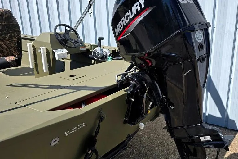 Slide: The Image of 2022 Lowe Roughneck RX1860 Rambler boat with Mercury outboard motor, parked near a metal building. - 8
