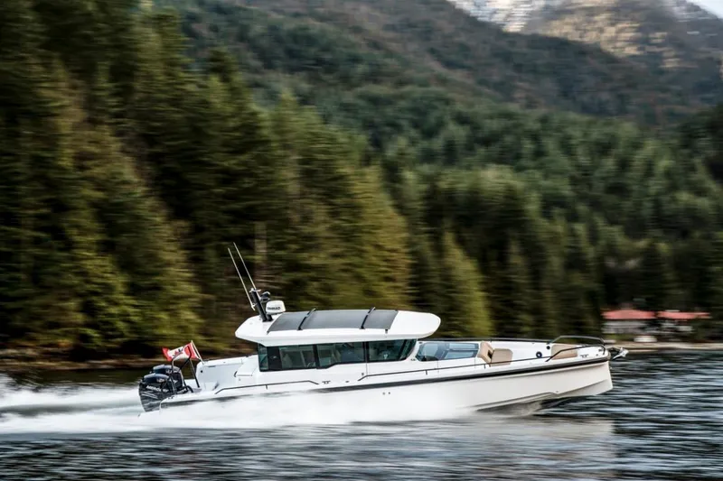 Slide: The Image of 2025 Axopar 37XC CROSS CABIN BRABUS Trim cruising on a scenic forest-lined waterway. - 11