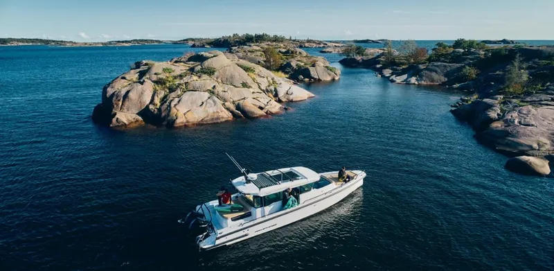 Slide: The Image of 2025 Axopar 37XC CROSS CABIN BRABUS Trim navigating scenic rocky waters. - 2