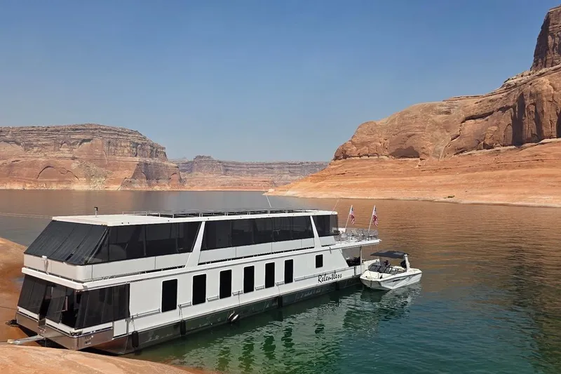 The Image of 2025 Sumerset Excellence Multiple Shares houseboat on serene lake with rocky cliffs. - 1