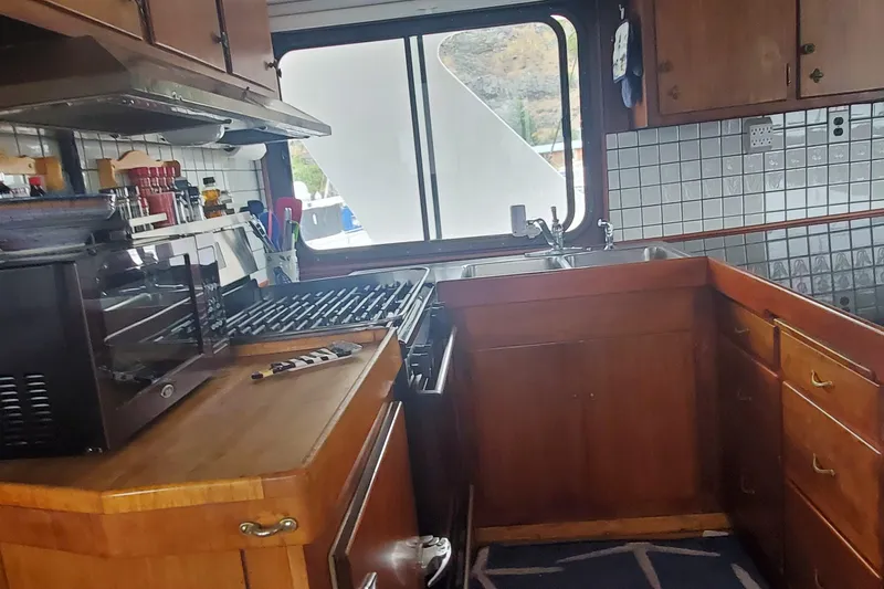 Slide: The Image of 1965 Tacoma Boat Works Bill Garden Motor Yacht kitchen with wooden cabinets and modern appliances. - 8