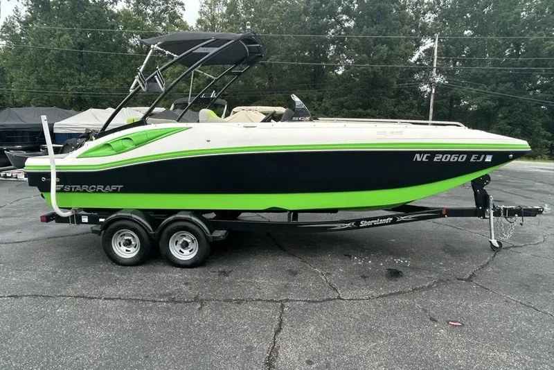 The Image of 2018 Starcraft 211 I/O SCX boat on trailer, green and black design, parked outdoors. - 0