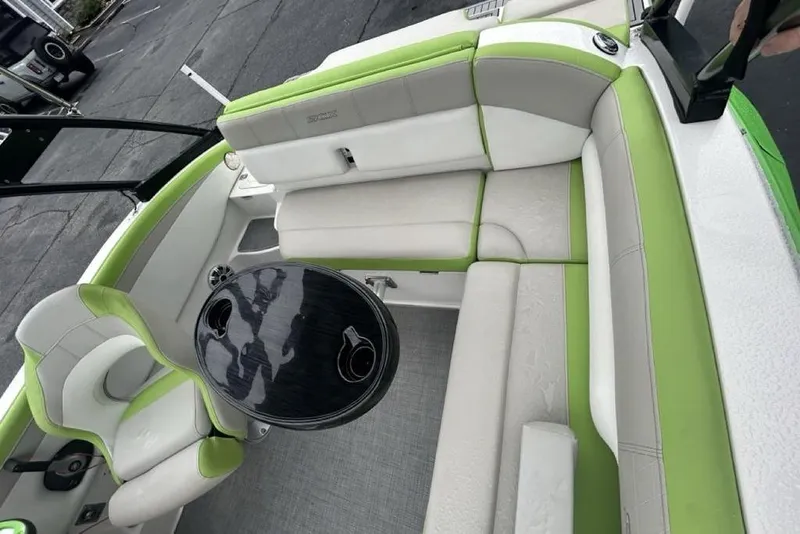 Slide: The Image of 2018 Starcraft 211 I/O SCX boat interior with green and white seating and round table. - 10