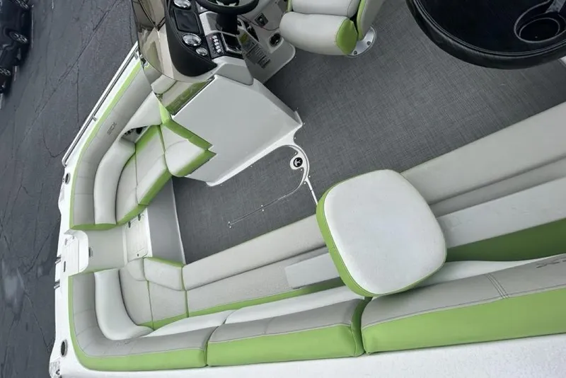 Slide: The Image of 2018 Starcraft 211 I/O SCX boat interior with green and white seating, steering console, and table. - 11