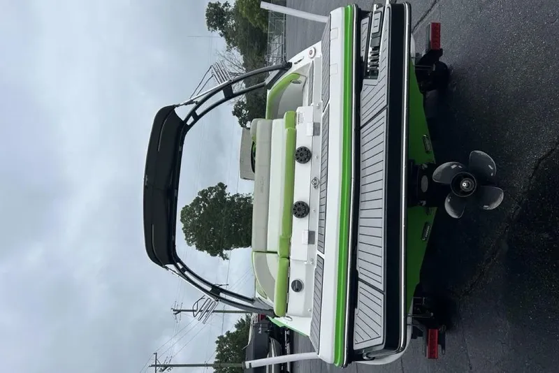 Slide: The Image of 2018 Starcraft 211 I/O SCX boat with green accents on a trailer, rear view. - 2
