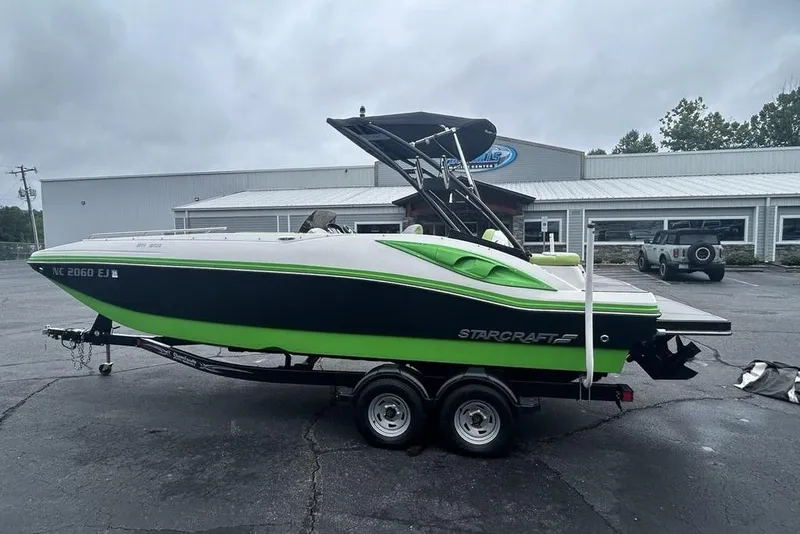 Slide: The Image of 2018 Starcraft 211 I/O SCX boat on trailer, parked outside a building. - 5