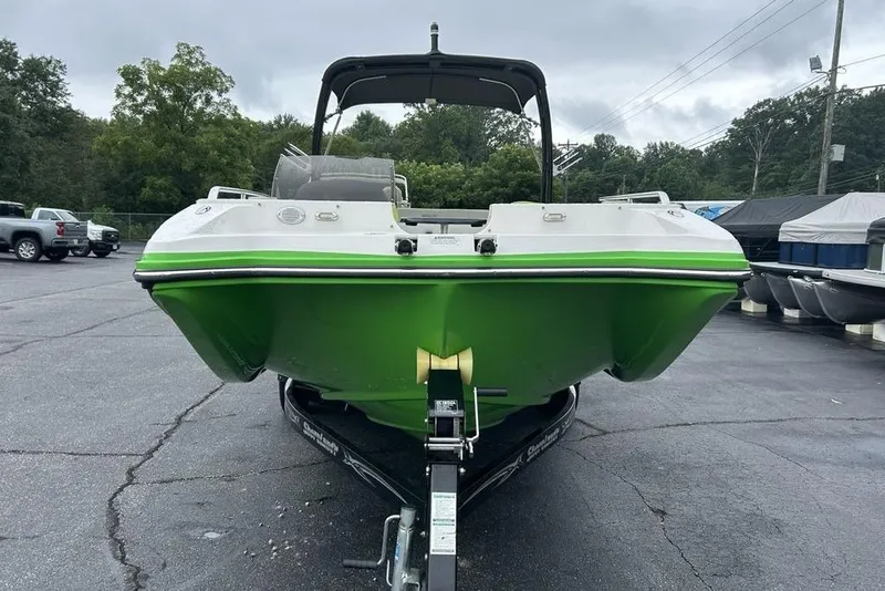Slide: The Image of 2018 Starcraft 211 I/O SCX boat with green hull on trailer in parking lot. - 3
