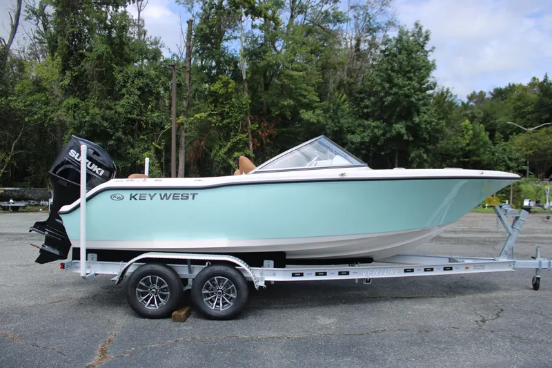 Slide: The Image of 2026 Key West 203 DFS boat on trailer, parked outdoors with trees in background. - 1