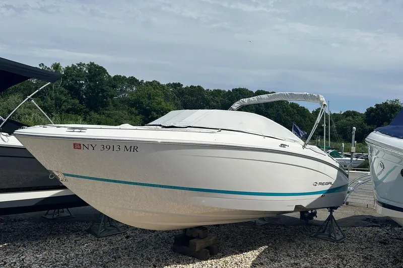Slide: The Image of 2020 Regal LS4 boat on display, white with blue accents, parked on gravel. - 11