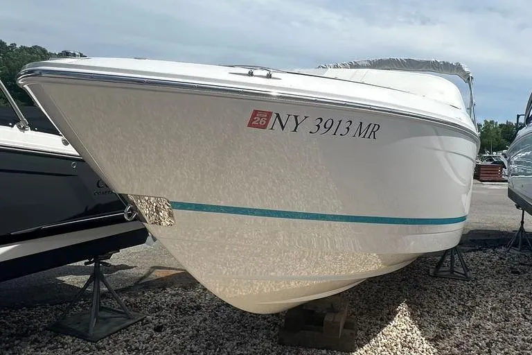 Slide: The Image of 2020 Regal LS4 boat on display, white hull with blue stripe, parked on gravel. - 12