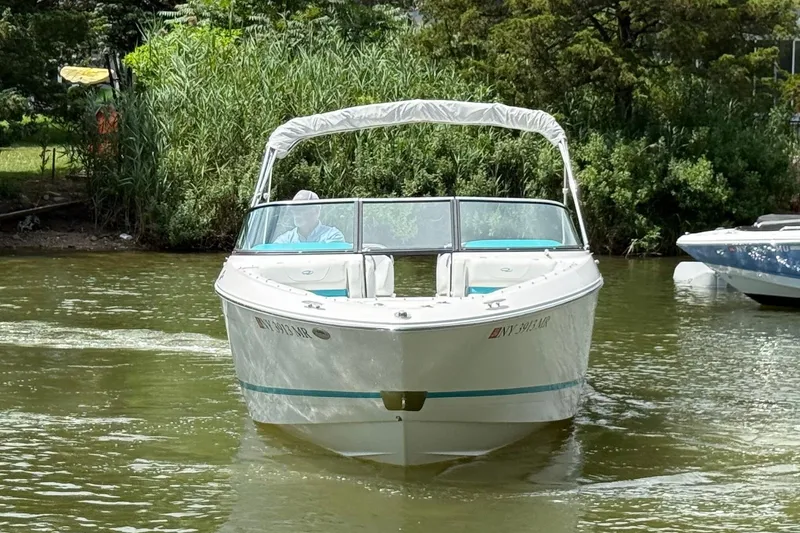 Slide: The Image of 2020 Regal LS4 boat cruising on a calm river with lush greenery. - 2