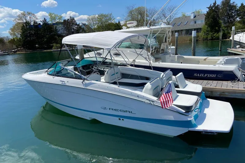 Slide: The Image of 2020 Regal LS4 boat docked, featuring a white canopy and American flag. - 3
