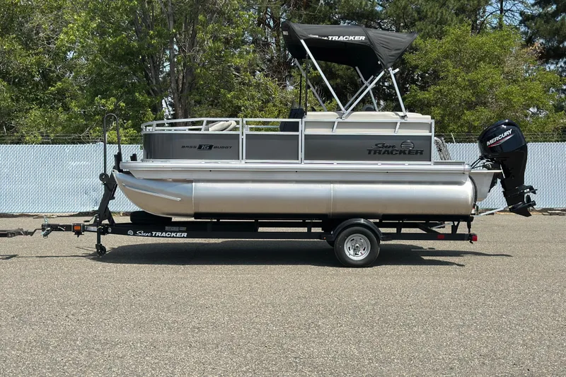 The Image of 2026 Sun Tracker Bass Buggy 16 DLX pontoon boat on trailer, outdoors. - 1