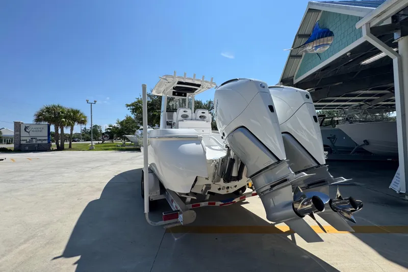 Slide: The Image of 2026 Caymas 291 boat with dual engines on a trailer, parked outdoors under clear sky. - 14