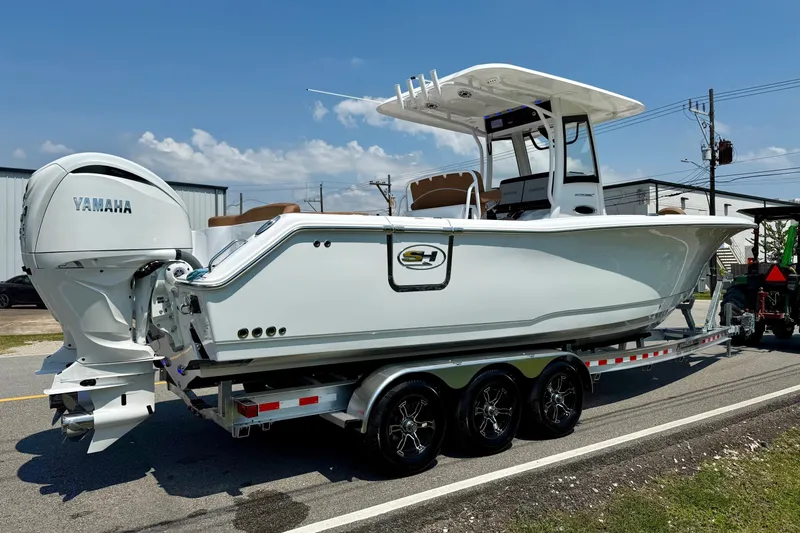 Slide: The Image of 2026 Sea Hunt Ultra 305 SE boat on trailer with Yamaha engines, parked outdoors. - 4