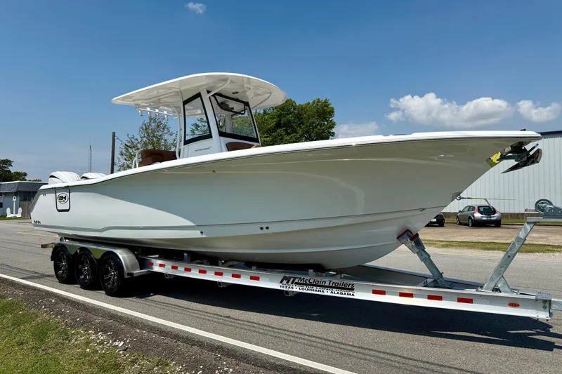 Slide: The Image of 2026 Sea Hunt Ultra 305 SE boat on trailer, parked on roadside under clear sky. - 5