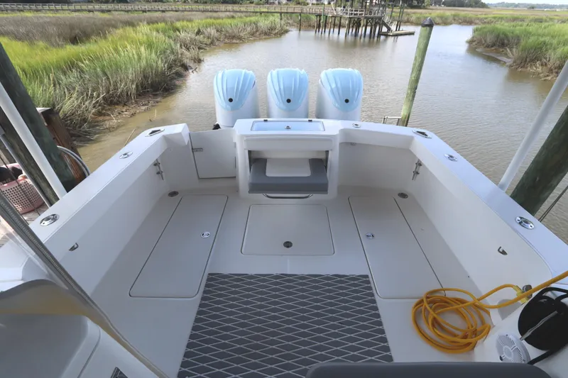 Slide: The Image of 2024 Albemarle 30 Express boat deck with triple outboard engines and storage compartments. - 22