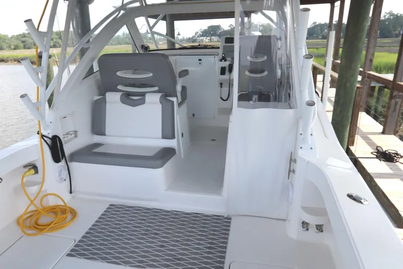 Slide: The Image of 2024 Albemarle 30 Express boat interior, featuring seating and helm, docked by a scenic waterway. - 35