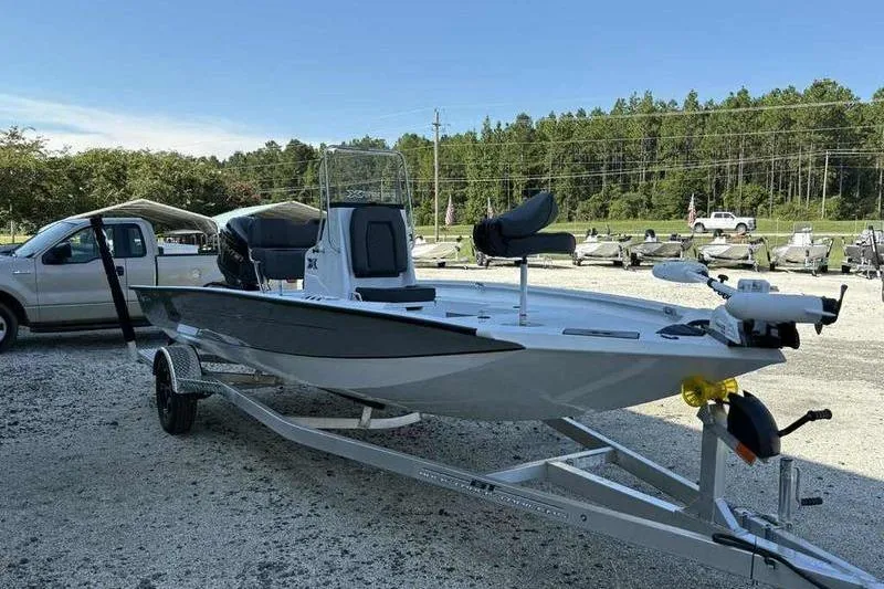 Slide: The Image of 2026 Xpress H20B boat on trailer, parked outdoors near trees and vehicles. - 3